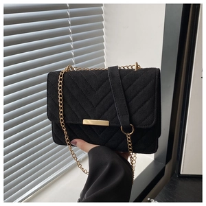 Detail of black suede shoulder bag with V-shaped quilting and gold metal buckle