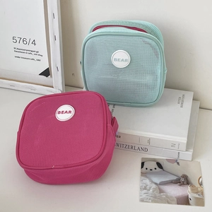 Detail of mesh storage bags in rose red and mint green with round BEAR logo patch