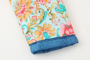 Detailaufnahme von hellblauem Blumendruckstoff mit jeansblauem Bündchen und feiner Naht