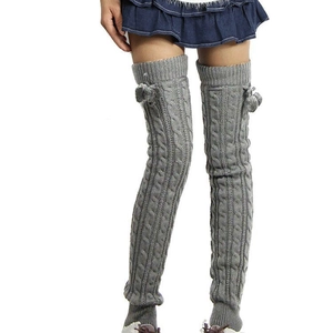 Detailed knit texture of grey over-knee leg warmers with soft pompom decorative balls