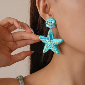 Close-up of model wearing turquoise starfish earrings with beads and rhinestones