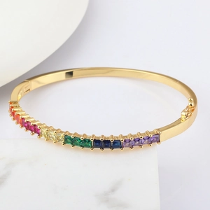 Macro detail of 18k gold plated bangle featuring rainbow gradient crystals and security clasp