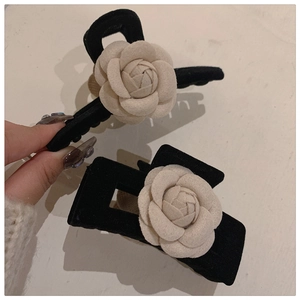 Close-up of elegant black velvet hair claws with 3D white camellia flower details