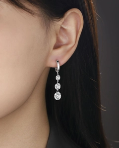 Close-up of 925 silver drop earrings with three graduated round moissanite stones on model