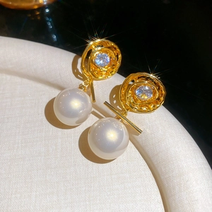 Detailed macro view of 14K gold plated swirl earrings with zircon and large round pearls