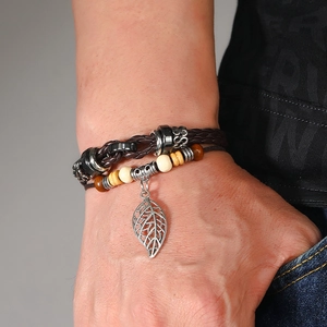 Detail of multilayer leather bracelet with leaf charm on wrist, set of two pieces