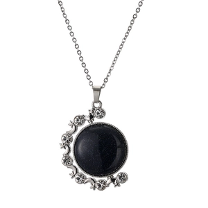 Macro shot of silver moon pendant featuring a deep blue star stone and sparkling crystals