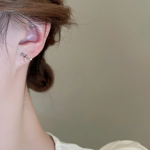 Close-up of pink heart and cupid arrow stud earring on ear with silver finish