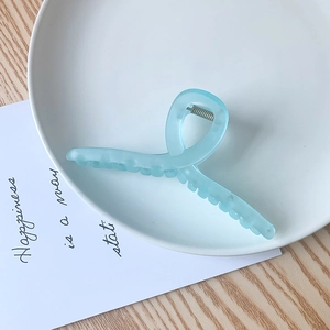 Détail d'une grande pince à cheveux bleu clair mat dans un plat en céramique
