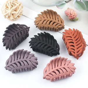 Set of six matte leaf-shaped shark hair clips in assorted earth tones on white surface