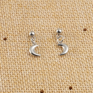 Détail de boucles d'oreilles en acier argenté avec breloques croissant de lune sur tissu
