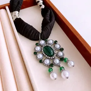 Vintage necklace with green oval gemstone, pearls, and black pleated cord in luxury style