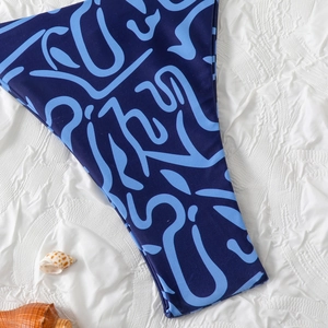 Detailed flat lay of blue patterned bikini bottoms with seashells on white fabric