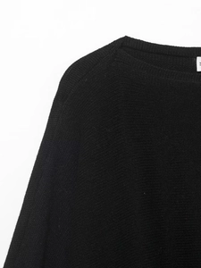 Detail of black knit sweater featuring puff sleeve design and soft texture closeup