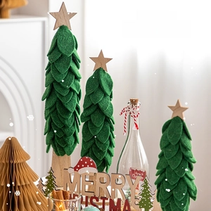 Three green felt Christmas tree table decorations with wooden bases in a cozy home setting