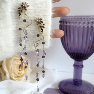 Gros plan de boucles d'oreilles papillon à pompons violets avec pendentifs gouttes d'eau