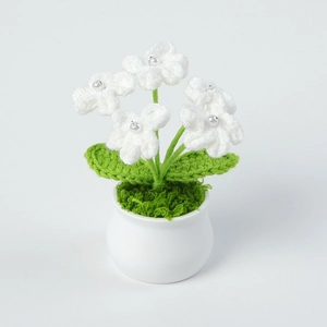 Close-up of handmade crochet forget-me-not plant with white yarn flowers and pearl centers