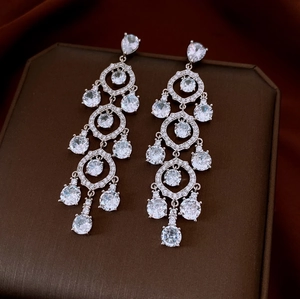 Detailed macro view of silver drop earrings with pavé zircons and crystal tassels