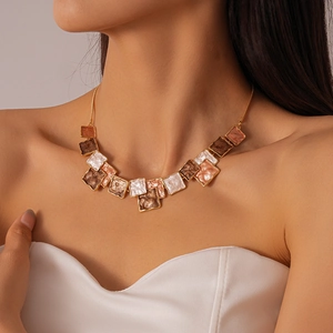 Detail of elegant gold-edged geometric resin pendants on the necklace worn by a model
