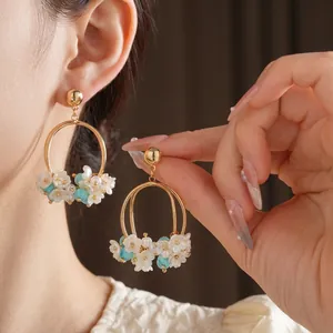 Floral hoop earrings with white flowers and blue beads worn by a female model