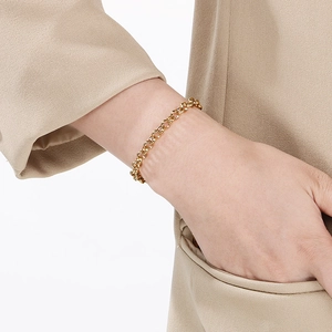 Close-up of chunky gold stainless steel chain bracelet on wrist with elegant pearl detail