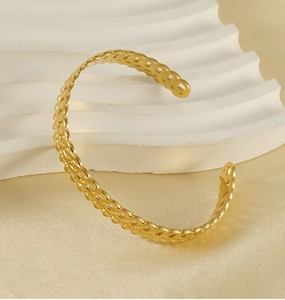 Gros plan d'un bracelet tressé évidé plaqué or 18K sur un support blanc élégant en soie