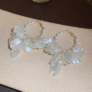 Detail of gold metal hoop earrings featuring white pearls and translucent petal tassels