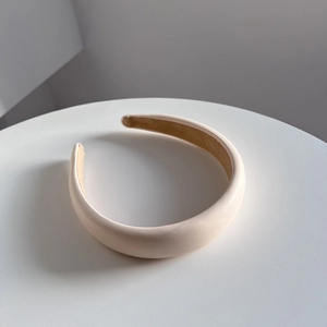 Detailed close-up of a padded beige PU leather headband with a soft brown inner lining