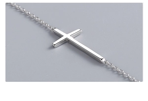 Macro side view of a polished S925 sterling silver cross pendant on a delicate cable chain