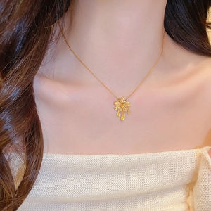 Detailed view of a gold-plated palm leaf necklace pendant worn by a model in soft lighting