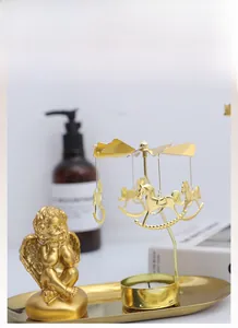 Golden spinning carousel candle holder with horse charms and cupid statue on tray