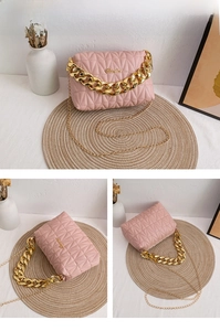 Detailed view of pink quilted crossbody bag with chunky gold chain handle and metal logo