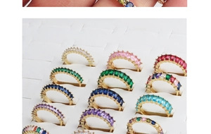 Detailed row of gold rings with multi-colored rectangular zircon crystals in a display box