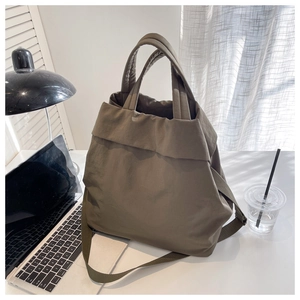 Deep khaki lightweight nylon tote bag shown in a professional lifestyle office setting