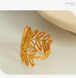 Macro shot of gold hollowed leaf-shaped ring with brushed metal texture and open band