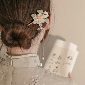 Detailansicht eines weißen Blumen-Haarstabs mit eleganten Metallquasten am Dutt