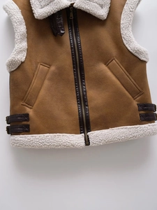 Close-up of brown suede and white fleece vest with metal zipper and buckle details