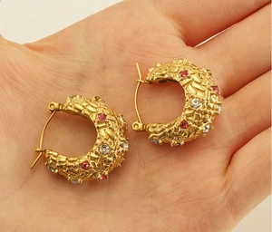 Detail of 18K gold plated hoop earrings with woven texture and sparkling pink crystals