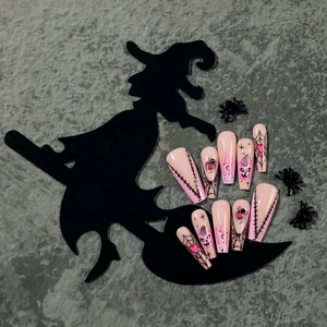 Pink Halloween press-on nails featuring black spider webs, pumpkin faces and 3D spider gems
