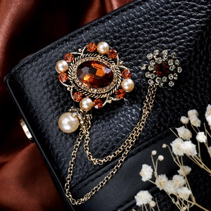 Macro shot of vintage brooch with emerald gemstone and golden tassel on black leather