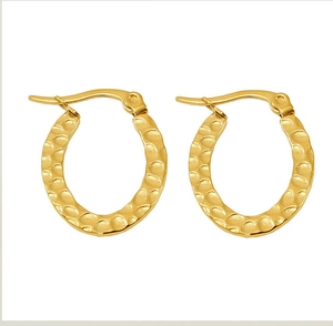Macro detail of gold-plated oval hoop earrings with textured hammered surface finish