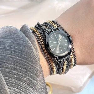 Detailed close-up of a stylish quartz watch with black dial and layered metal chain strap