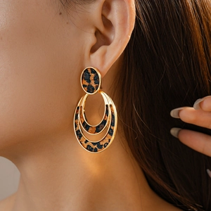 Close-up of golden multi-layer oval leopard print drop earrings on a fashion model