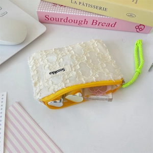 Close-up of lace makeup bag featuring a yellow zipper and fluorescent green strap