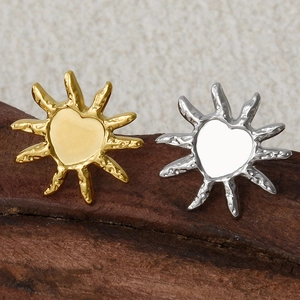 Macro shot of 18k gold and silver sunburst heart earrings with hammered texture finish