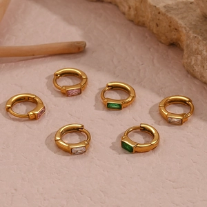 Détail de boucles d'oreilles huggie dorées avec pierres en zircon rose, vert et blanc