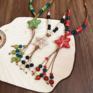 Detail view of handmade ceramic starfish pendant necklaces with tassel beads and woven cord