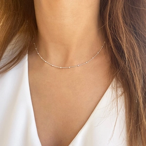Primo piano di una collana di perline in argento S925 minimalista indossata