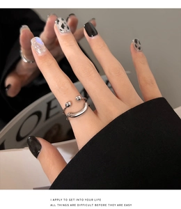 Close-up of a silver smiley face double-layered open ring worn on index finger