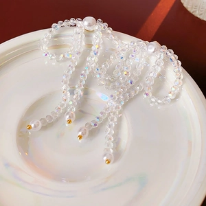 Detailed macro view of crystal bow earrings with hanging pearls and golden bead accents